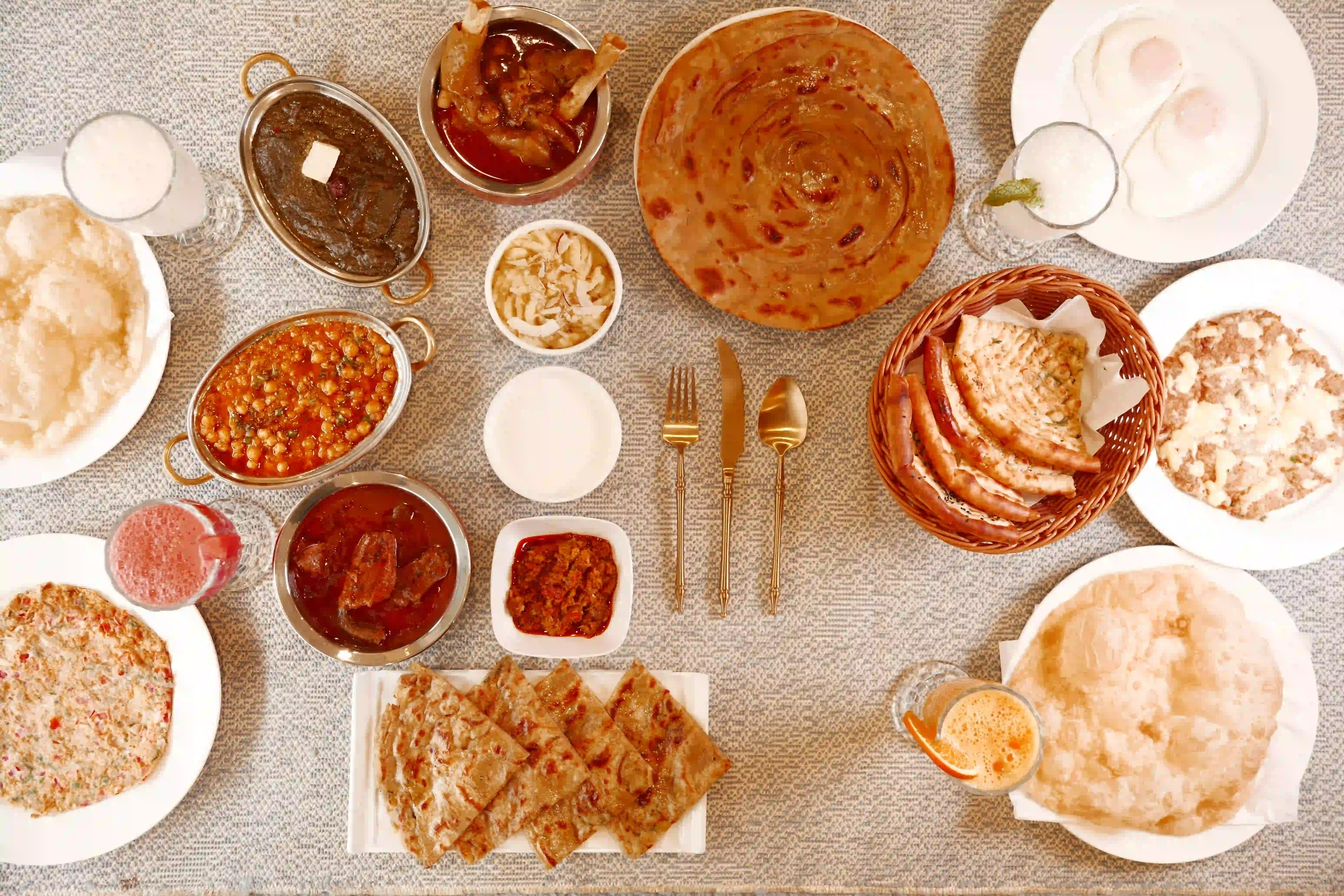 A full nashta spread of halwa puri, channa, paya, nihari, paratha and chai at Zafran Kitchen Ajman
